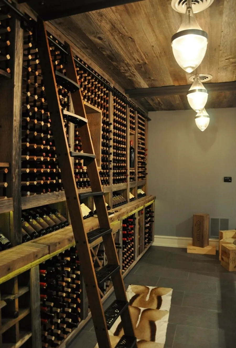 Custom basement wine cellar with floor-to-ceiling wood wine racks, reclaimed beam ceiling, and library rolling ladder, Naperville IL