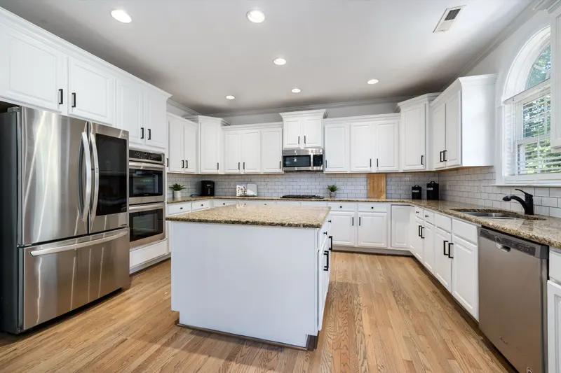 White kitchen with matte black cabinet hardware and a granite island