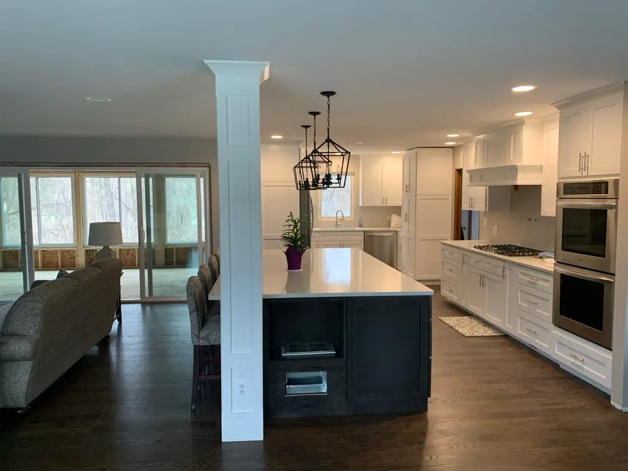 Open-concept kitchen with white cabinetry, dark island, quartz countertops, and lantern-style pendant lighting, Naperville IL
