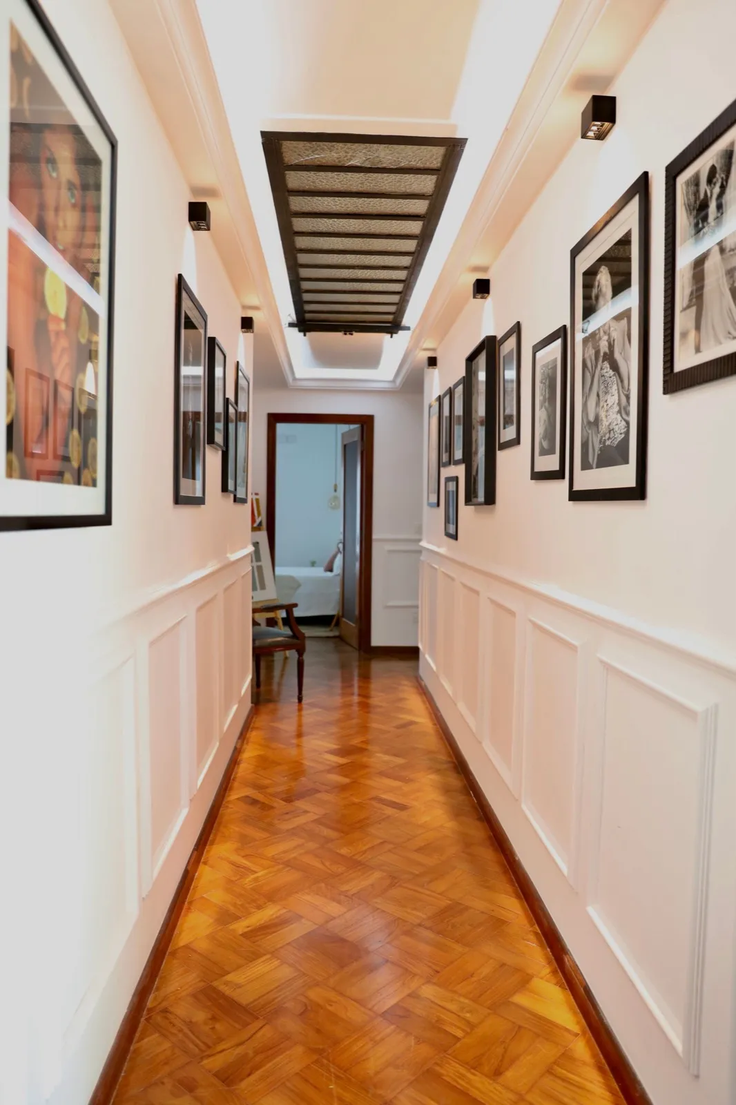 Hallway with white panel wainscoting running the length of the corridor