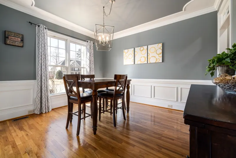 Gray dining room with white wainscoting and a modern lantern pendant